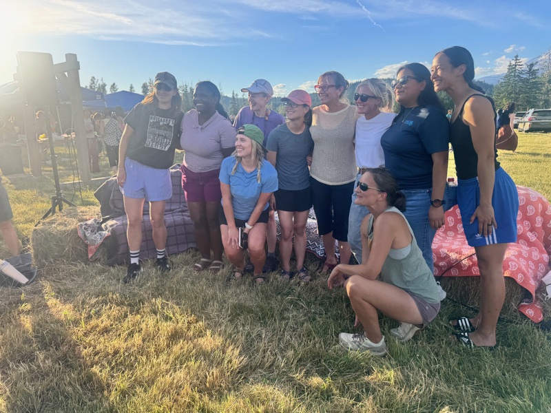 A larger group of GEA Alliance board members and guests gathered outdoors in late-afternoon light, posing together with mountains in the distance